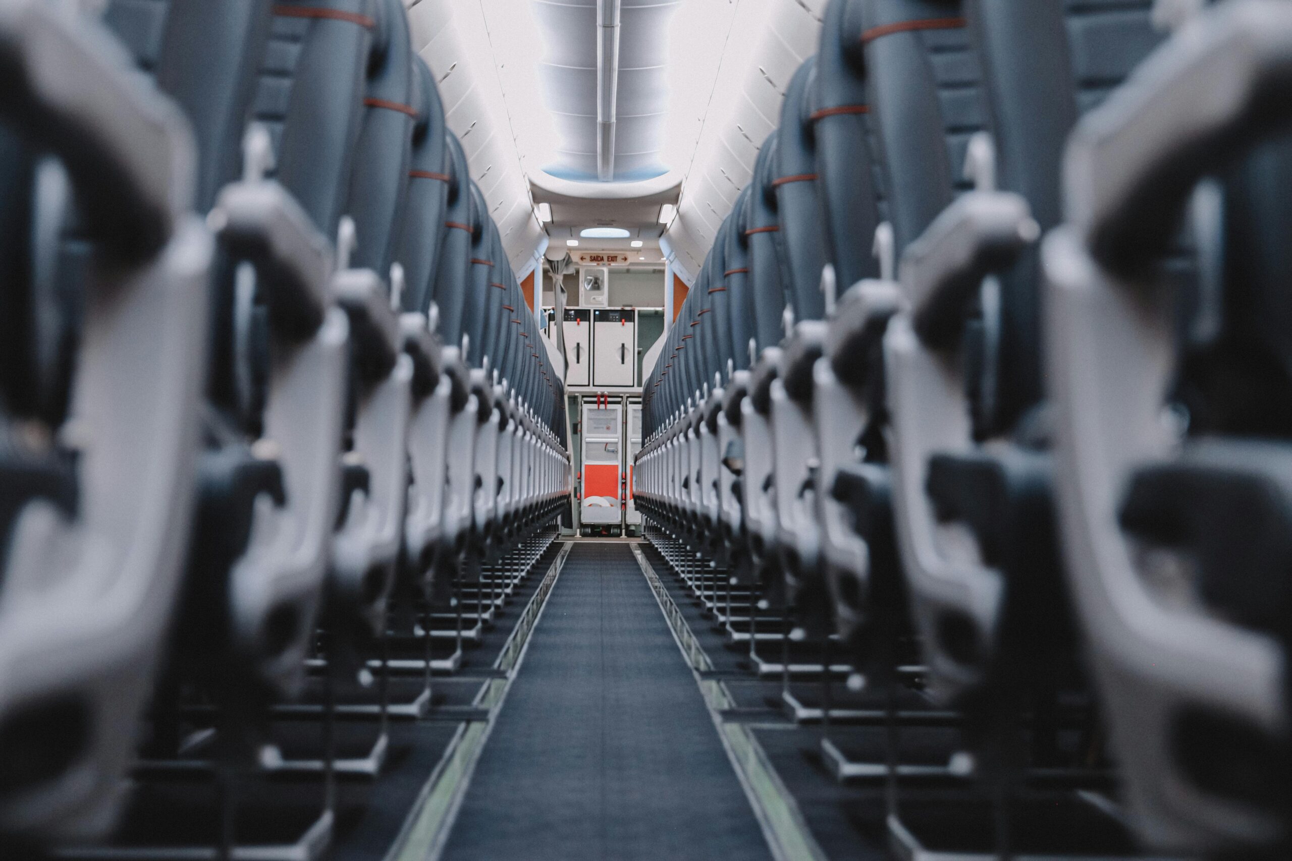 Symmetrical view through an empty airplane cabin showcasing rows of blue seats.